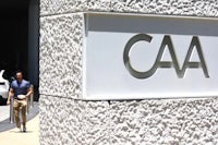 a man walks past a caa sign in front of a building